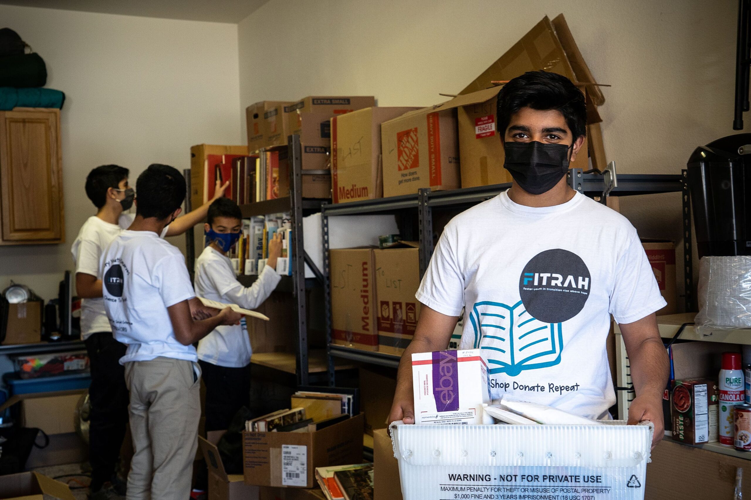 A young Fitrah Youth volunteer holds a box of books.